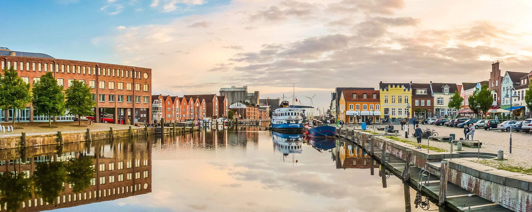 Der Hafen von Husum ist das maritime Herz der Stadt und geprägt von historischen Krabbenkuttern und bunten Giebelhäusern, die entlang der Kais stehen