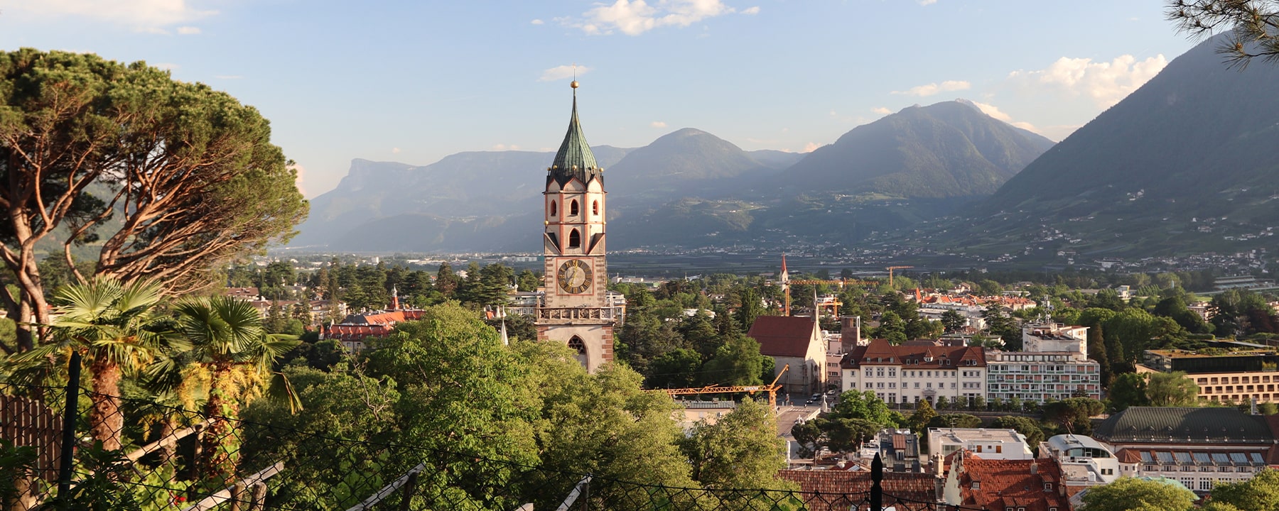 Reiseführer Meran: Die Stadt liegt eingebettet zwischen den Südtiroler Alpen und dem Etschtal, wo mediterrane Vegetation auf alpine Gipfel trifft und ein mildes Klima die Region prägt