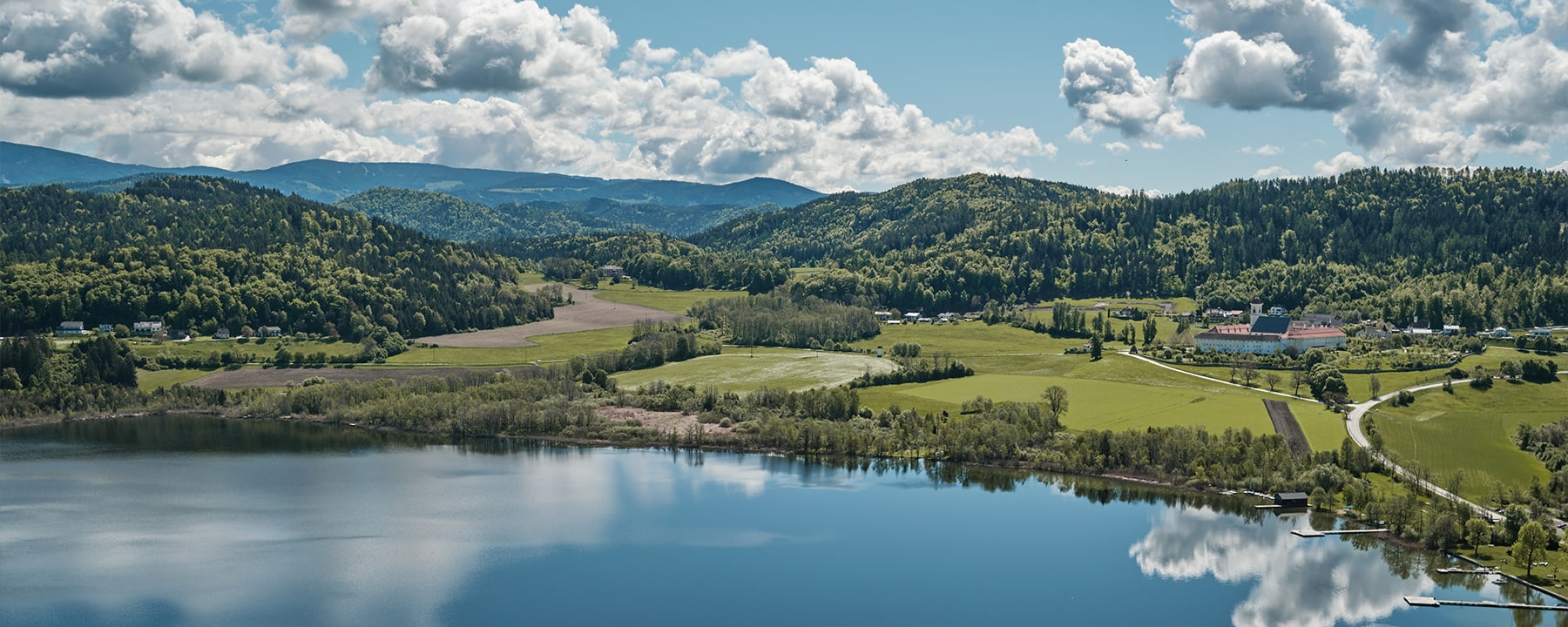 Der Längsee lädt mit seinem klaren Wasser zum Entspannen ein, während das nahegelegene Stift St. Georgen durch seine historische Architektur und den idyllischen Klostergarten erfreut